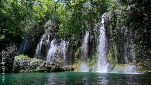 Scenic view of a hidden jungle waterfall with lush green foliage and crystal clear water.