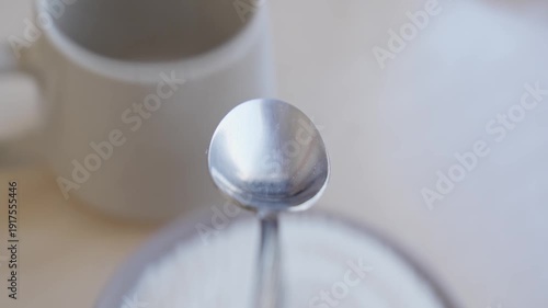 Silver spoon glistens as it scoops up mound of sugar from bowl. Scoop sugar with spoon and pour it into cup. POV. Spoon as it lifts sugar from bowl. Close-up in 4K, UHD