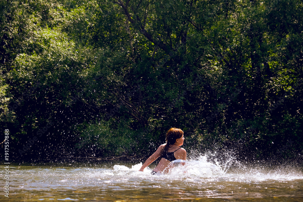 Fototapeta premium Happy family time outdoors. Playful teenager girl swimming and splashing in the river. Happy carefree moments. A fun time of discovery, play, and adventure. Having fun in travel, vacations. Humor