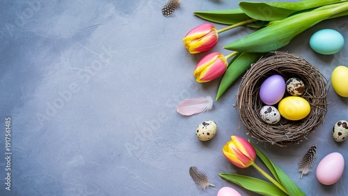 Colorful Easter eggs in a bird's nest surrounded by tulips and feathers on a textured blue-gray background.