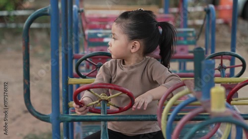 slow motion of child girl playing with a steering wheel toy on a playground
