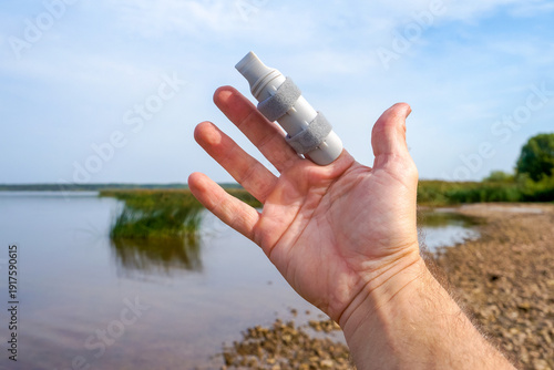 Obraz na płótnie Hand wearing a finger splint outdoors, symbolizing recovery and rehabilitation f
