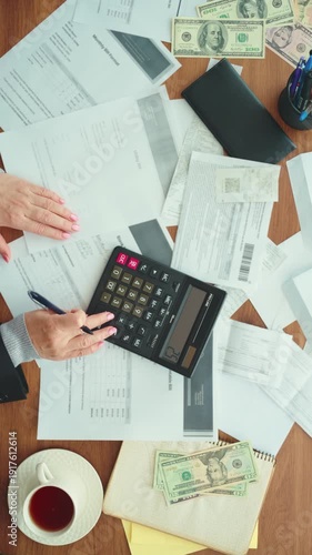 text is blurry. Hands accountant working at office desk using calculator planning corporate budget. woman taking notes checking utility bills taxes bank account balance. calculating expenses top view