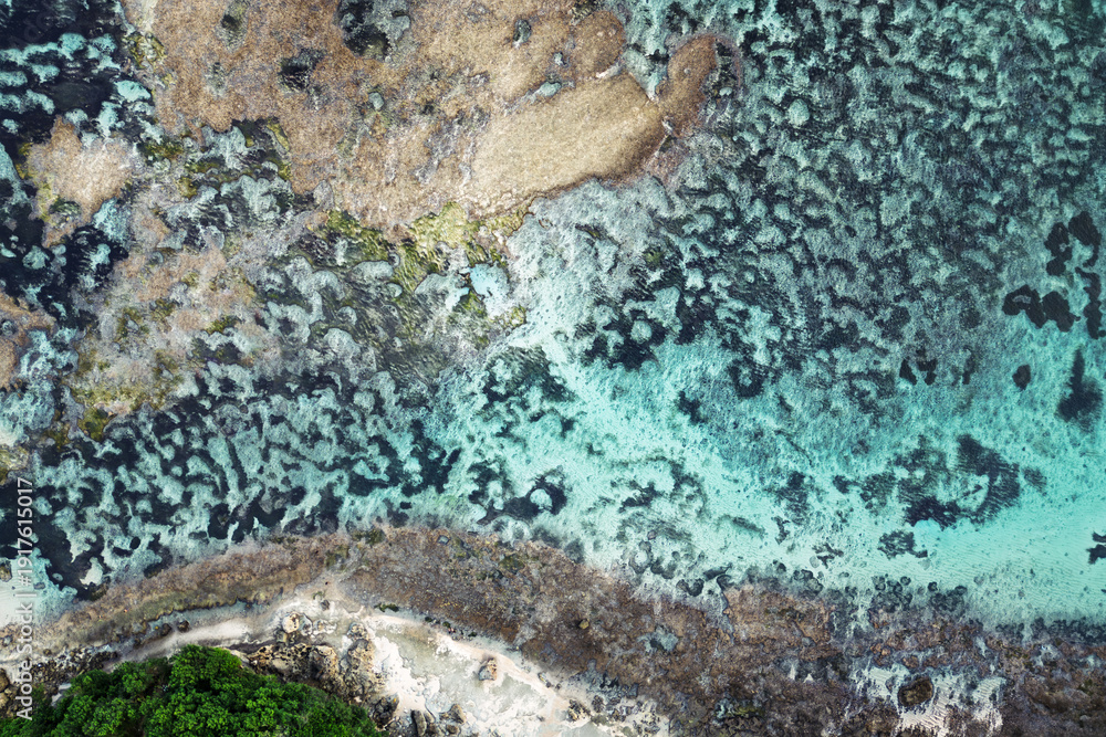 Obraz premium Aerial tropical shoreline with turquoise water over coral reef, organic patterns for nature background, summer travel and serenity.