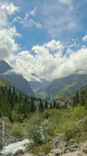 Time lapse of clouds moving over mountains. Meadow in mountains in front alps mountains. Fast-moving clouds revealing an alpine valley landscape with forests and mountain scenery. Dynamic atmospheric 
