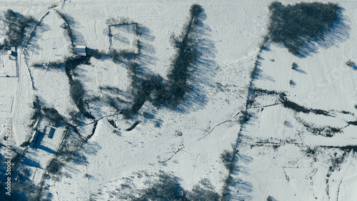 Overhead drone shot of winding river creating abstract patterns across snow covered terrain