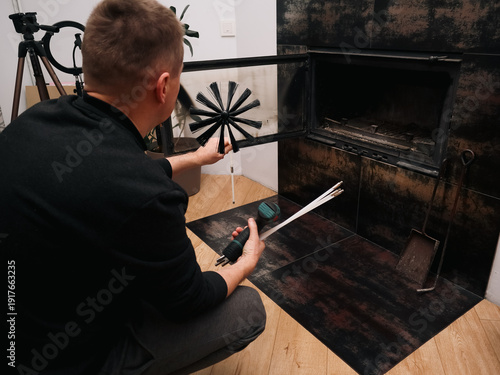 Man preparing to clean a modern indoor fireplace with a professional chimney brush.