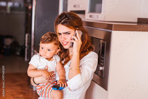 Annoyed mother with her son talking on the phone at home