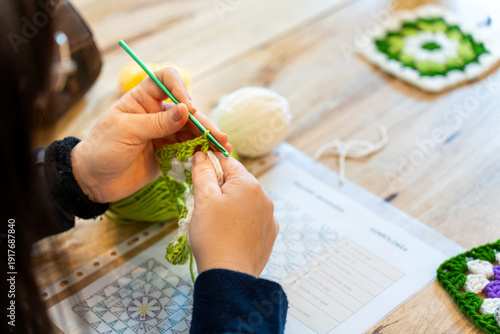 Tableau sur toile Person crocheting granny square following pattern instructions