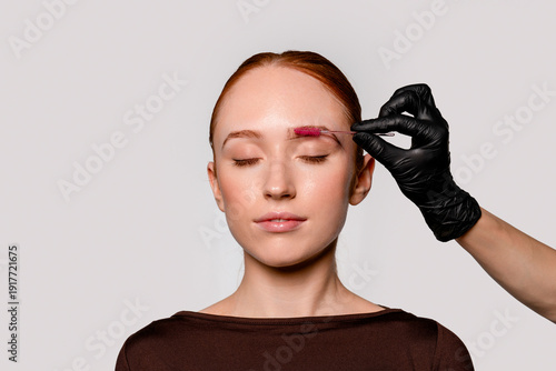 Stylist shapes eyebrows for a client in a beauty salon during a cosmetic session