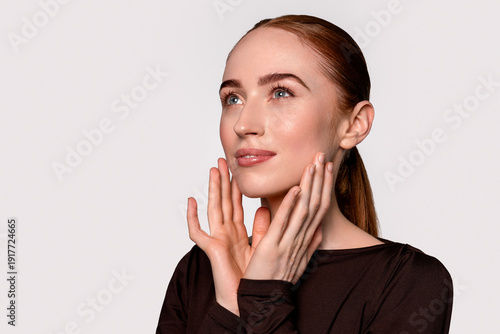Foto Woman with light skin and long brown hair touches her face in a studio setting d