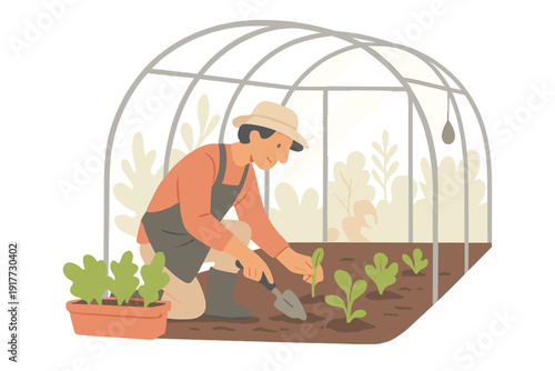 A man wearing a hat and apron plants small green seedlings in a garden bed inside a greenhouse structure. He uses a hand trowel to dig in the soil while kneeling on the ground.