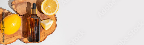 Vitamin C cosmetics. Facial serum or essential oil in brown glass bottles with dropper dispenser, fresh lemons on wooden stand. Skincare concept, acid peels, spa treatments. Cosmetic packaging mockup