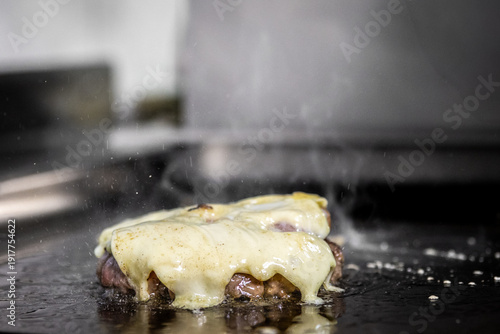 Angus beef burger patty cooking on griddle