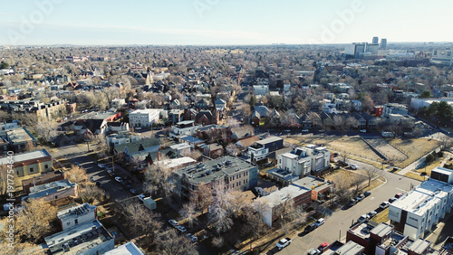 Aerial view neighborhoods east of Capitol Hill open toward the downtown ridge along Colfax Ave. Crisp daylight enhances shingle patterns, muted lawns and bare tree silhouettes, Denver, Colorado