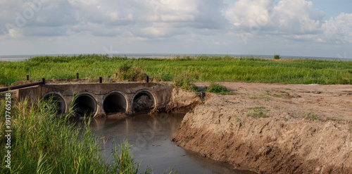 Foto Old drainage culvert structure spanning shallow water channel in rural wetland n