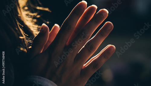 Close-up of two hands pressed together with sunlight in the background.
