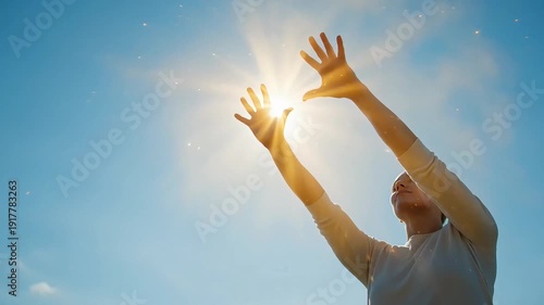 A woman reaches her hands towards the sun, embracing its energy and light for natural immune support under a clear blue sky.