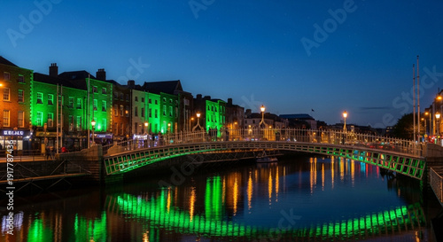 Illuminated pedestrian bridge in Dublin city center at night with green lights reflecting on the river water