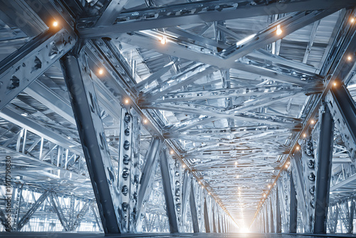 Wallpaper Mural Steel truss structure with metallic beams and bolts forming modern industrial framework illuminated by warm lights, creating dynamic and futuristic architectural scene Torontodigital.ca