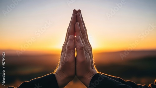 Hands in prayer pose against a vibrant sunset sky symbolizing hope and spirituality.