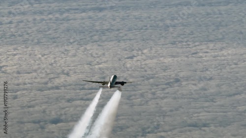 aerial top video view of an wide-body passenger airplane with contrails produced by each engine, flying in front below on same track in the same direction - 4k aerial video footage