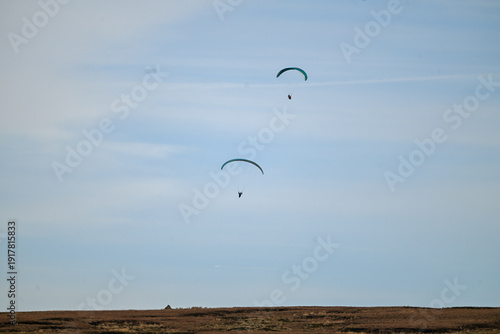 Bild auf Leinwand Paragliders sailing the prevailing winds over moorland.