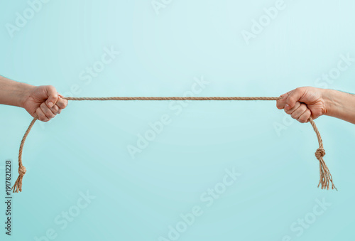 Two people pulling a rope in opposite directions, concept of conflict, power struggle, tension and confrontation, teamwork breakdown and competition