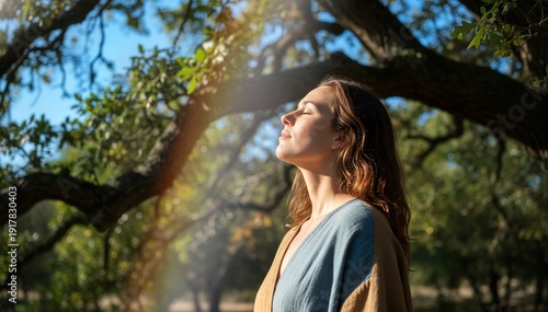 Young woman enjoying nature while standing under a tree in sunlight  