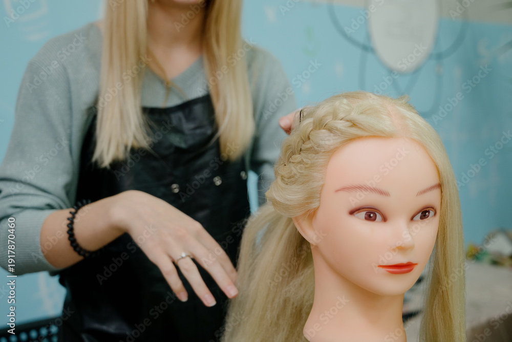 Naklejka premium A hairdressing student practices braiding hair on a mannequin