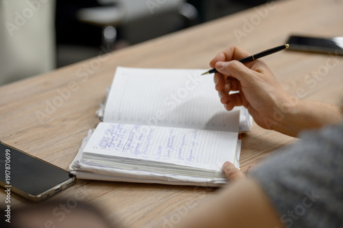 Close-up of a woman's hand with a pen taking notes in a paper notebook