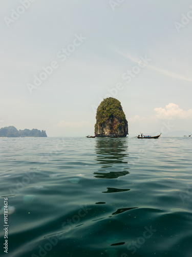Low angle view of sea stack with long-tail boats and jellyfish