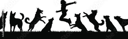 Silhouette of a child jumping with eight dogs on grass