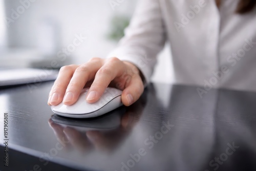 Person using white computer mouse on black desk in office setting with hand on table JPG image
