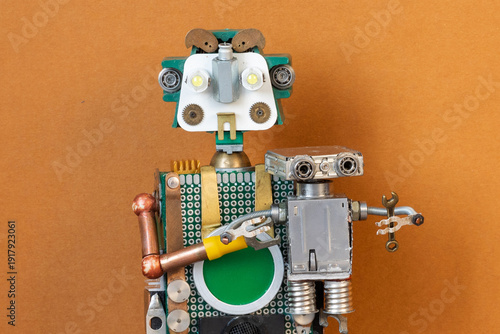 Kind green robot cradling a baby robot holding a toy wrench. Caretaking moment, robot family poster