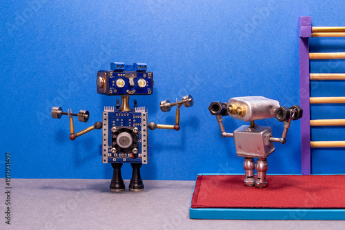 Big blue toy robot trainer holding dumbbells demonstrating exercise to small silver robot athlete. Sports coaching concept, fitness training poster