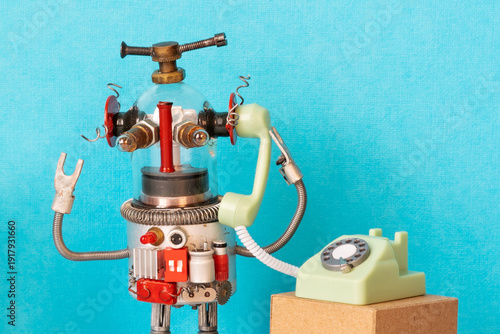 Glass-headed toy robot holding old rotary phone receiver near ear. Customer support assistant concept, robotic voice chat poster