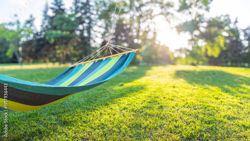 Quadro em tela Colorful hammock hanging in sunny green garden backyard, blurred background