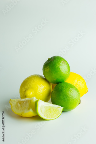 Lemons and Limes and lemon wedges against a white background.