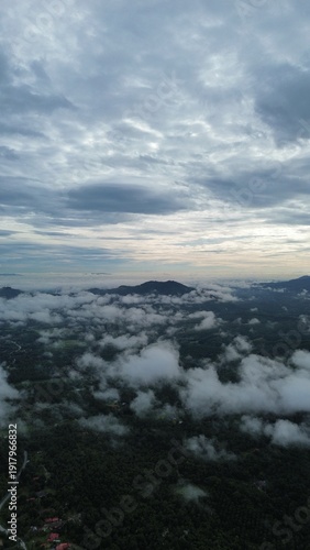Canvastavla Drone aerial view of misty clouds floating over green forest and rural village in a mountainous landscape during early morning