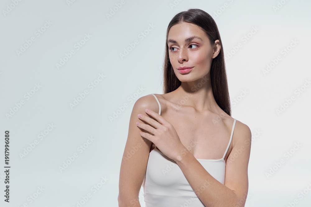 Fototapeta premium Beautiful young woman poses gracefully in soft light showcasing elegance and natural beauty