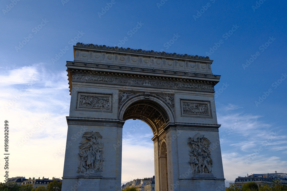 Fototapeta premium Majestic low-angle view of the Arc de Triomphe in Paris at dusk under a clear blue sky