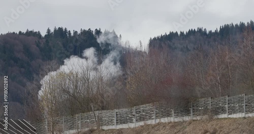industrial smoke stack behind noise protection wall from highway