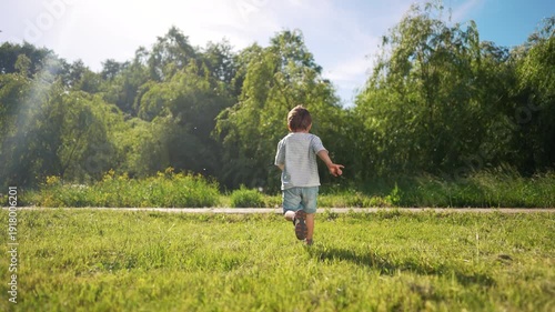 Child running in the park. Child is running outdoors. Young girl in a red dress and a young man in a blue dress and a red sweater looking at the trees in summer. Kid sprinting through the lifestyle.