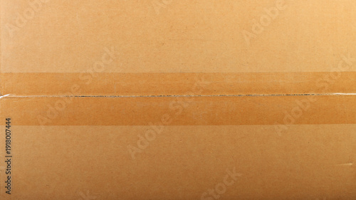 Texture of brown corrugated cardboard with clear adhesive tape, macro shot.