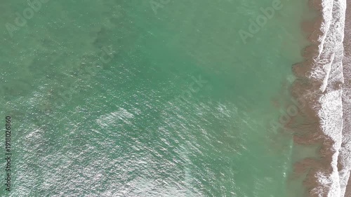 Ocean waves roll onto the shore at a sunny beach location today