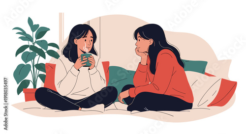 Two young women, best friends or sisters, are sitting on a bed having a heartfelt conversation while drinking hot beverages.