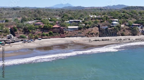 Sunny beach with waves and boats in a coastal area