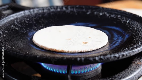 Close Up Of A Person Cooking Chapati On A Tawa Over A Gas Stove With Blue Flames
