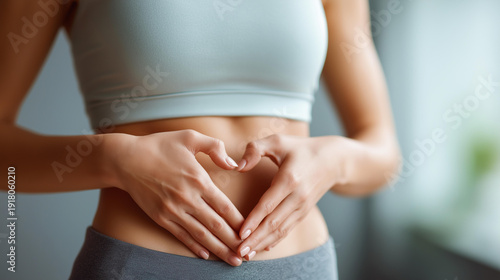 Fitness heart hands woman in gym with belly, gut health and inspiration for body goals, sport stomach athlete, weight loss digestion support in wellness routine, defocused background, with copy